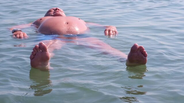 A man lies relaxed on the surface of a salt lake. The increased content of salt and minerals keeps the swimmer on the surface of the water. Salts of the Dead Sea