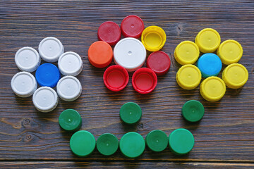 Colorful plastic bottle caps on dark rustic table. Floral mosaic, ecology concepts. Copy space