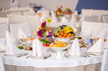 Table setting in a restaurant. Table decorated with flowers and beautiful appetizers salads on a white tablecloth. Holiday dinner.