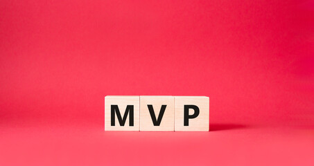 MVP symbol. Wooden cubes with words MVP. Beautiful red background. Business and MVP concept. Copy space.