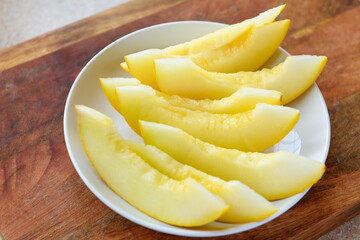 a plate full of sliced melon on a wooden board, the concept of fresh fruit and healthy food