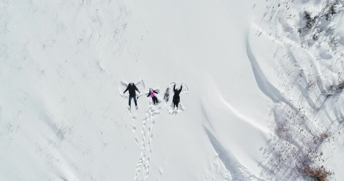 happy family lies in the snow and makes an angel