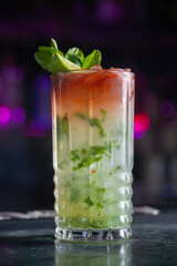 cocktail with lime and herbs on a marble table of a bar