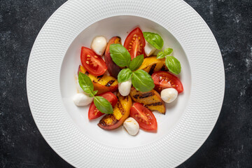 Grilled peach salad with mozzarella, green basil and sauce , close up, top view