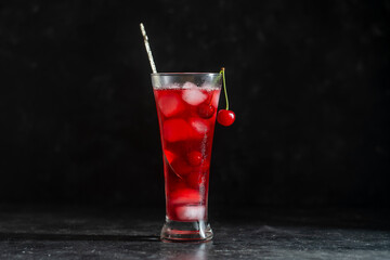 Fresh red cherry cocktail with ice cubes in glass on black background. Summer iced refreshing drink