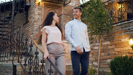 A young couple talking while moving down the stairs leaving their house and going to dinner.