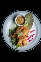 zenith view of breaded with panko shrimps plate in a restaruant in black background