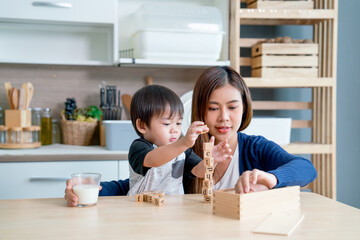Asian mother enjoy to play wooden jigsaw puzzle together in area of kitchen of their house and they look happiness.
