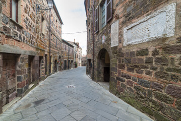 Italian medieval village details, historical stone alley, ancient marrow street, old city stone buildings architecture. Radicofani, Tuscany, Italy.