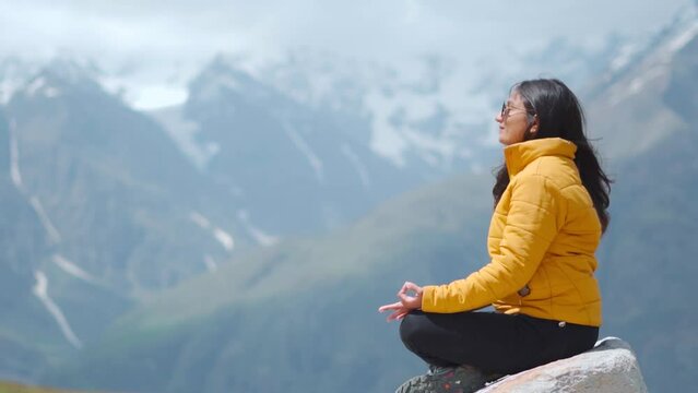 Young Indian woman practicing yoga in snow covered mountains at Manali, Himachal Pradesh, India. Harmony, meditation, healthy lifestyle, relaxation, yoga, self care, mindfulness concept. Yoga Himalaya