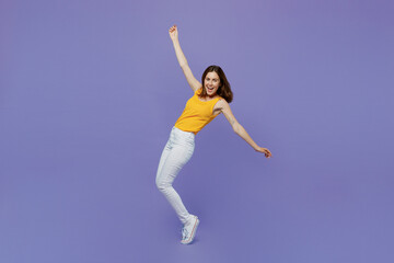 Fototapeta na wymiar Full body young woman 20s she in yellow tank shirt stand on toes with outstretched hands leaning back dance isolated on plain pastel light purple background studio portrait. People lifestyle concept