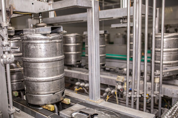 Brewery, bottling beer on aluminum kegs on conveyor lines. Industrial work, automated modern food and beverage production.