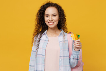Young black teen girl student she wear casual clothes backpack bag hold books hold in hand mock up of credit bank card isolated on plain yellow color background High school university college concept