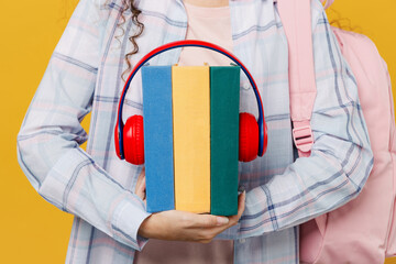 Fototapeta na wymiar Cropped young black teen girl student she wear casual clothes backpack bag holding books with headphones isolated on plain yellow color background. High school university college audiobooks concept.