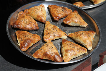 Traditional Uzbek patties (samsa) with chicken meat, lying on a large metal dish