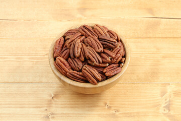 Pecan nuts in bamboo bowl on wooden table. Closeup