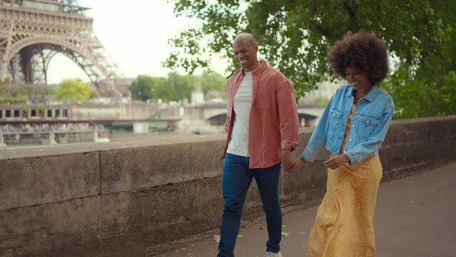 Happy multiethnic beautiful couple in love visiting Paris. Young man and woman on vacation in the french capital city, walking and doing activities around the eiffel tower area	