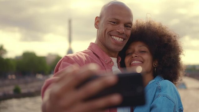 Happy multiethnic beautiful couple in love visiting Paris. Young man and woman on vacation in the french capital city, walking and doing activities around the eiffel tower area	