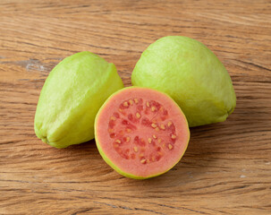 Red guavas with half fruit over wooden table