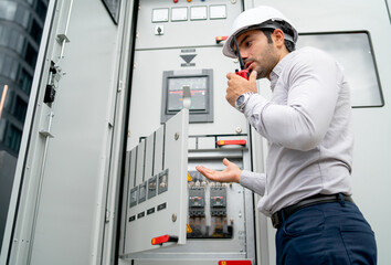 Different actions and working of engineer man hold walkie talkie and sometime use to contact his coworker and stay in front of electrical control panel.