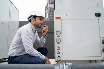 Fototapeta premium Engineer man or technician sit and use walkie talkie to contact his team for maintenance of tank system in construction site.