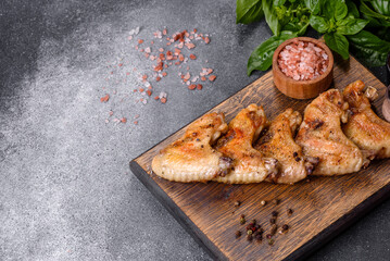 Baked chicken wings with sesame seeds and sauce on a wooden cutting board