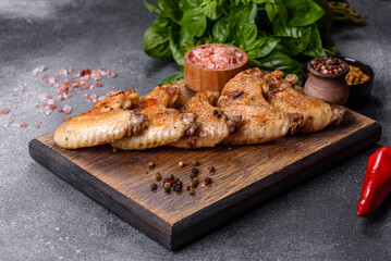 Baked chicken wings with sesame seeds and sauce on a wooden cutting board