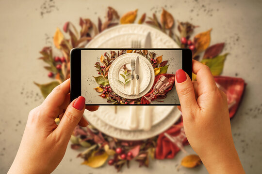 Woman taking photo of Thanksgiving table setting with smartphone for social media.