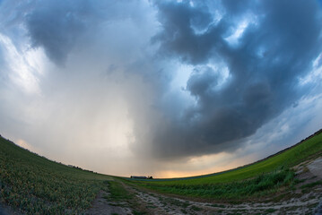 Fisheye view of a dramatic looking thunderstorm over the plains. On the left side of the photograph...