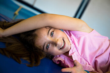 Pretty, light-eyed girl lying on mats in her school gymnasium.