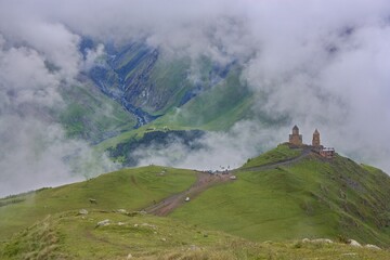 The Holy Gergeti Trinity Church in clouds in Georgia, the Caucasus with mountains in the background