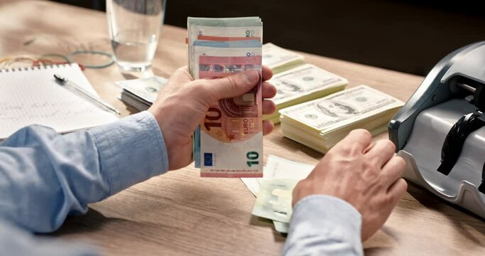 Close up of male hands counting euros bills money sitting at table in office. Bank worker calculating euro currency. Financial concept, cash credit. Man counts cash banknotes. Wealth. Business concept