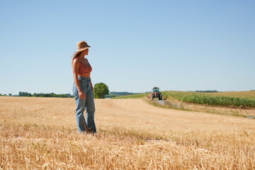 A beautiful young woman standing in a wheat field on a sunny day in a countryside