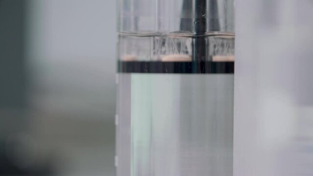 a tablet was thrown into a flask of water and dissolved by stirring water with a tablet. in the background flasks with leaves. close-up