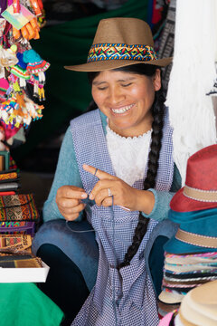 Mujer latina sonriendo y tejiendo en una t&iacute;pica tienda de recuerdos