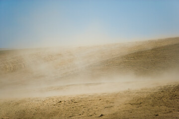 Farmland is eroded by high winds, forming dust clouds.