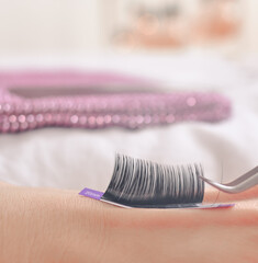 Stripe with fake lashes sticking on the hand of eyelash technician . High quality photo