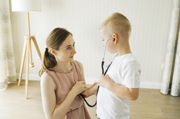 The boy plays doctor with his mother, puts a stethoscope on his ears.