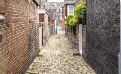  A cobbled back street between terrace housing, back gates and outside loos