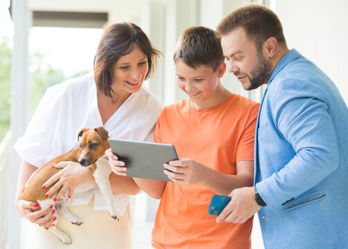 Portrait Of A Happy Joyful Family. Dad, Mom And Son Use A Tablet. With Cheerful Joyful Emotion.internet Shopping Online Banking Video Call Technology Concept