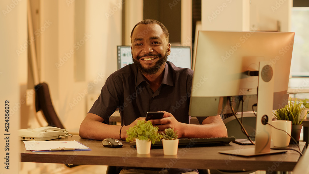 Poster portrait of african american man using smartphone app on computer, planning business presentation an