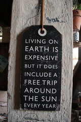 Photo of a  positive quote against a wall .  Living on earth is expensive but it does include a free trip around the sun. 