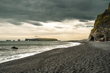 Vík í Mýrdal, Iceland - July 3, 2022 Panoramic view of the iconic South Coast's Reynisfjara black sand beach and the basalt columns under mountain Reynisfjall. Located near the village of Vik.
