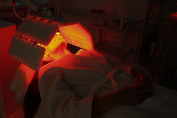 Express facial treatment with led therapy. Beautiful girl on a light therapy procedure. LED lamp...