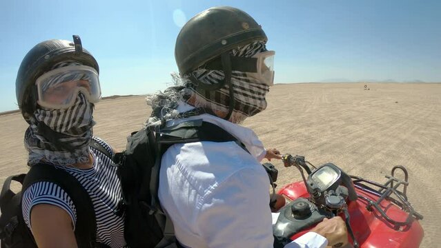Young copule of tourists having fun speeding on quad bike riding in dunes of Egypt