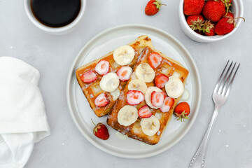 Square belgian waffles with strawberries berries,bananas,condensed milk,honey on plate, cup of coffee espresso. Tasty breakfast, sweet dessert food.selective focus, close up top view flat lay