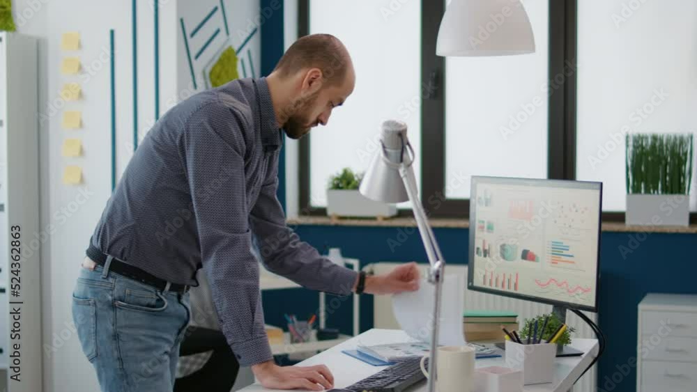 Poster sales consultant looking at business charts on files and computer, analyzing financial statistics fo
