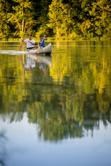 Obraz premium Air Force service member takes his sons canoeing at sunset out on the lake.