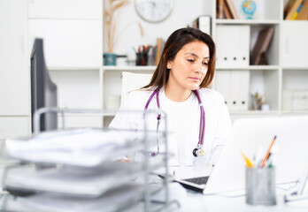 Portrait of a young female doctor working at a computer in the clinic in the resident's office