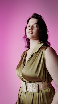 Plus size model posing on a plain background in the studio, vertical video